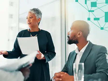A senior leader speaking with a notepad in hand while a colleague listens