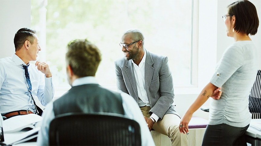 Laughing coworkers discussing project at workstation in office