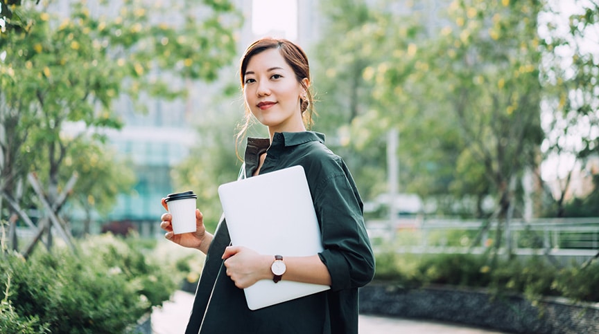 Asian businesswoman holding laptop smiling and representing leading with purpose