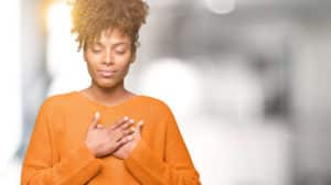 image of a woman holding hand over heart representing dealing with burnout and overcoming burnout