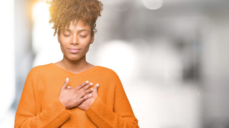 image of a woman holding hand over heart representing dealing with burnout and overcoming burnout