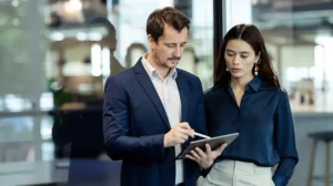 Two professionals look at a tablet together, considering a guide to decision making for leaders