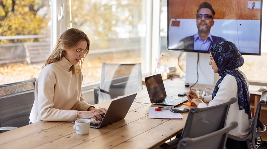 An image of 3 people working in a hybrid setting
